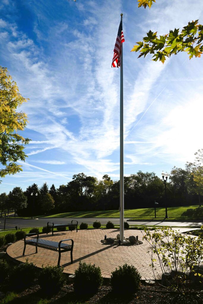An American flag and bench overlook engraved bricks on the Memorial Patio at Bethany Village